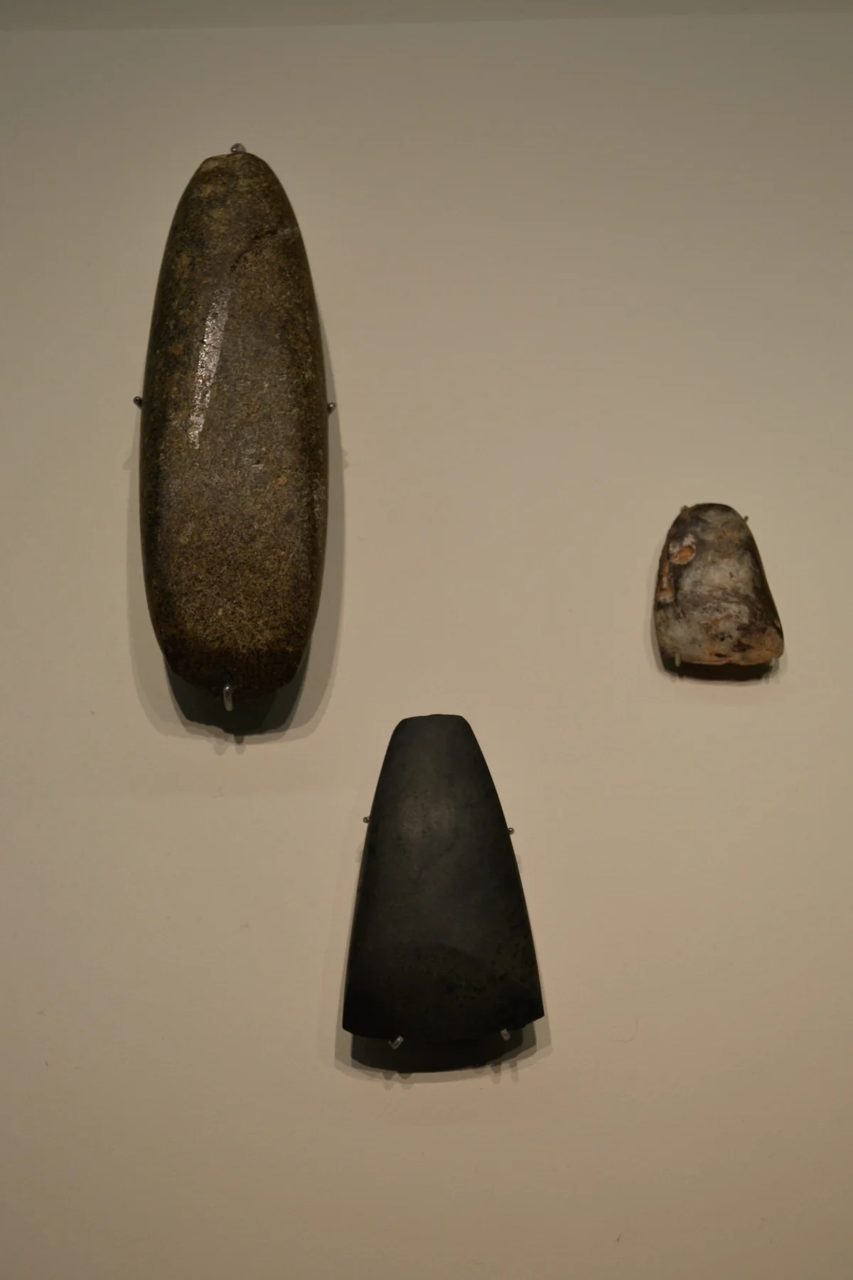 Cincel y hachas de piedra pulida expuestos en el Museo Arqueológico Nacional; fotografía contextual.