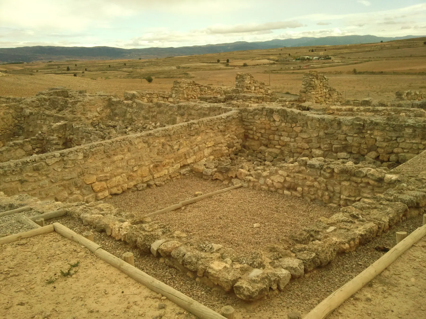 Restos de muros y habitaciones excavadas en el yacimiento de Alto Chacón, con la llanura al fondo.
