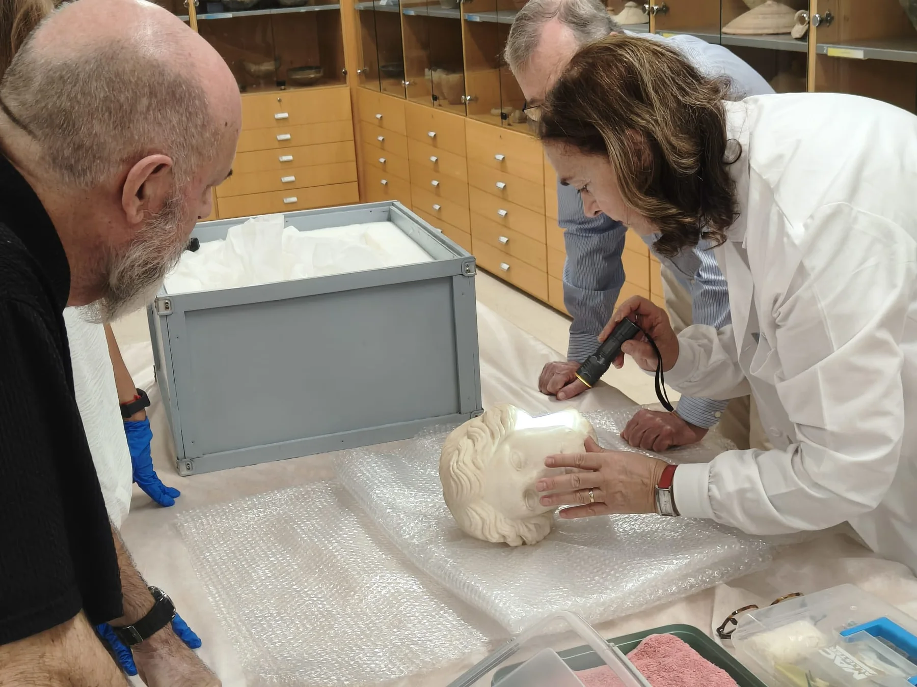 Examen de la cabeza escultórica de la Venus de Alicante sobre una mesa del museo.